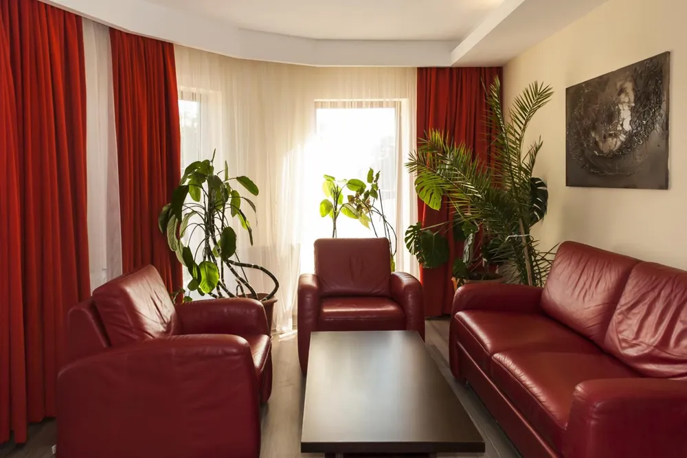 Livingul apartamentului cu canapea și fotolii din piele roșie