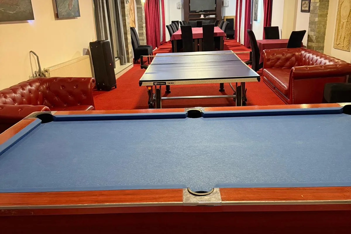 Sala de jocuri, cu biliard, tenis de masă și canapele din piele