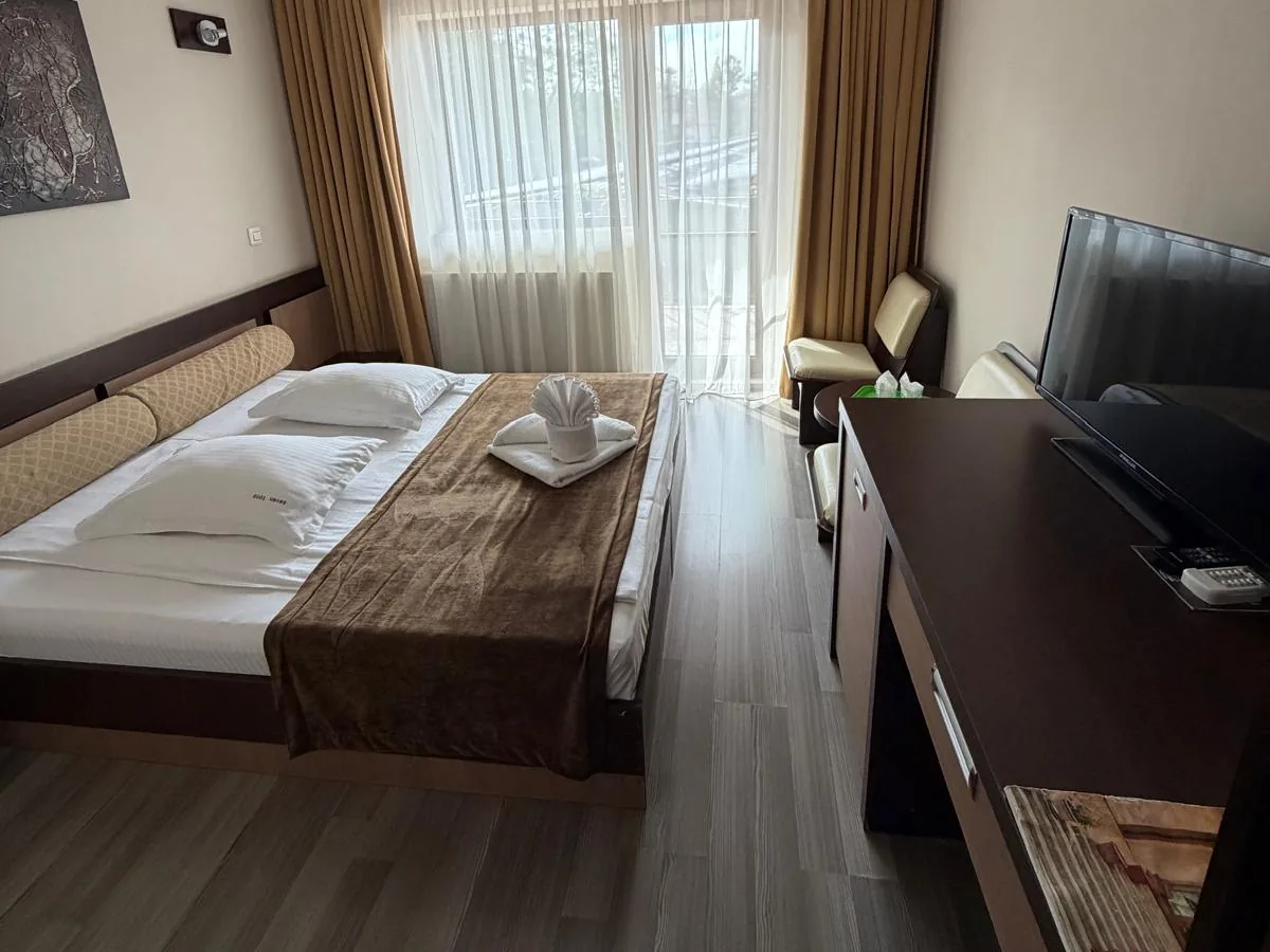 Cameră dublă cu pat matrimonial, perdele aurii și ușă spre balcon