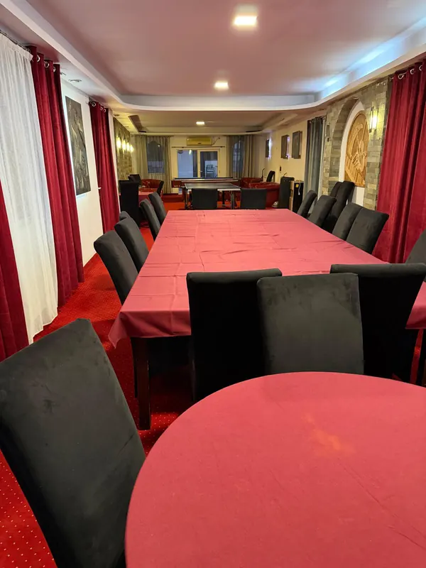 Sala de evenimente, cu masa lungă pregătită pentru invitați